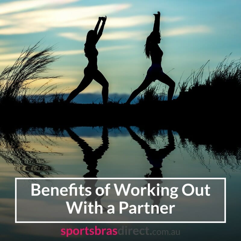 Silhouette of two women stretching by a lake.
