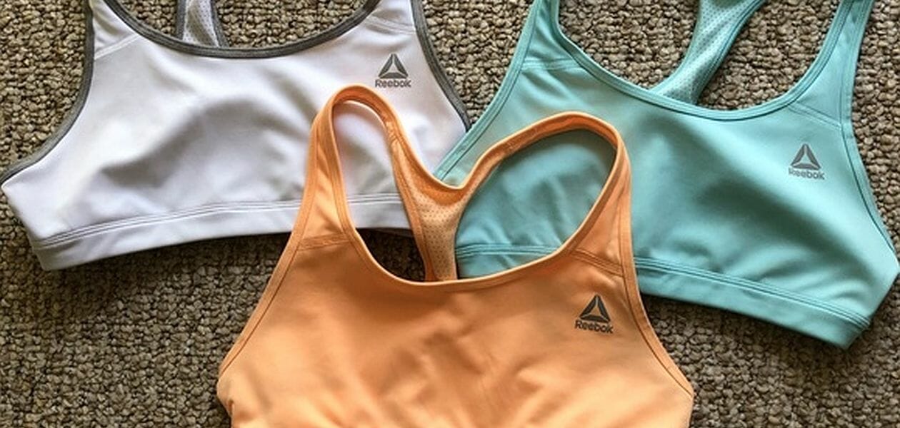 Three sports bras laid on the carpet together.
