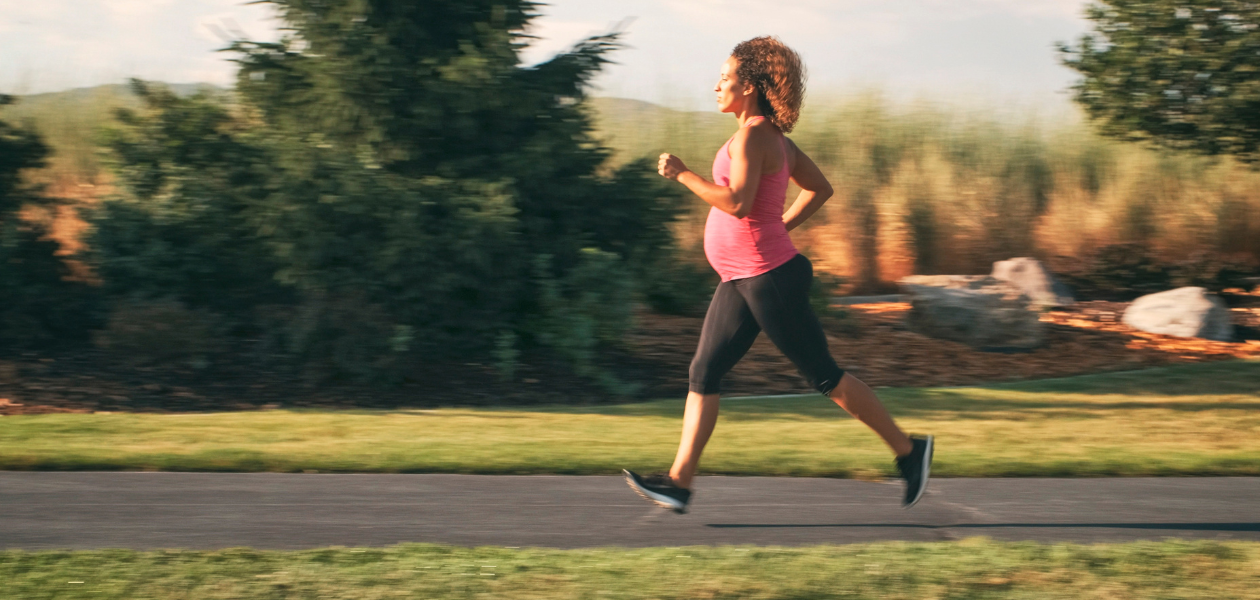 Pregnant woman running on path.
