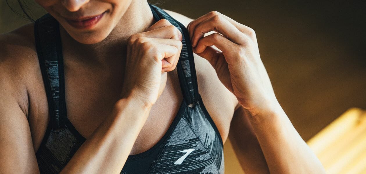 Woman in dark sports bra adjusting her shoulder strap.