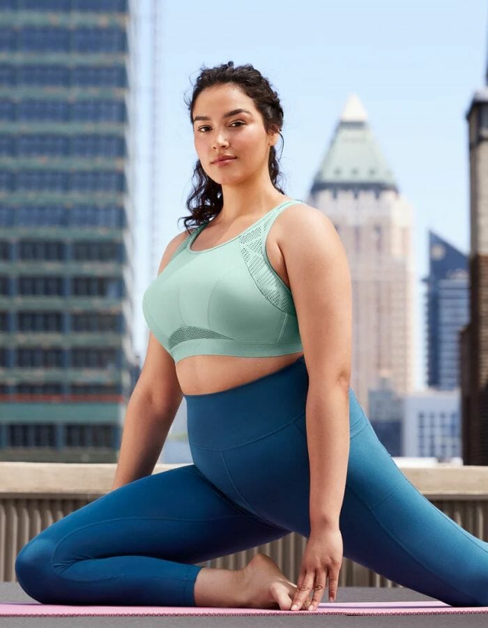 Woman stretching in a light green sports bra.