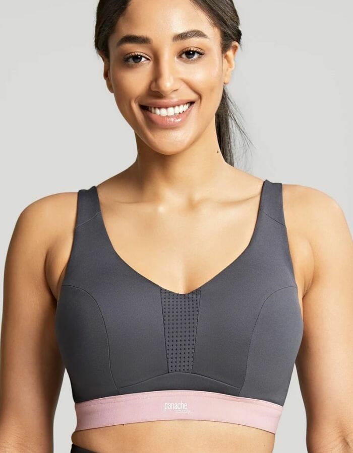 Woman wearing a dark grey sports bra with pink trim.