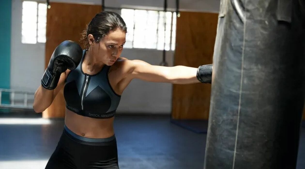 Women in a zip front sports bra hitting a gym bag.