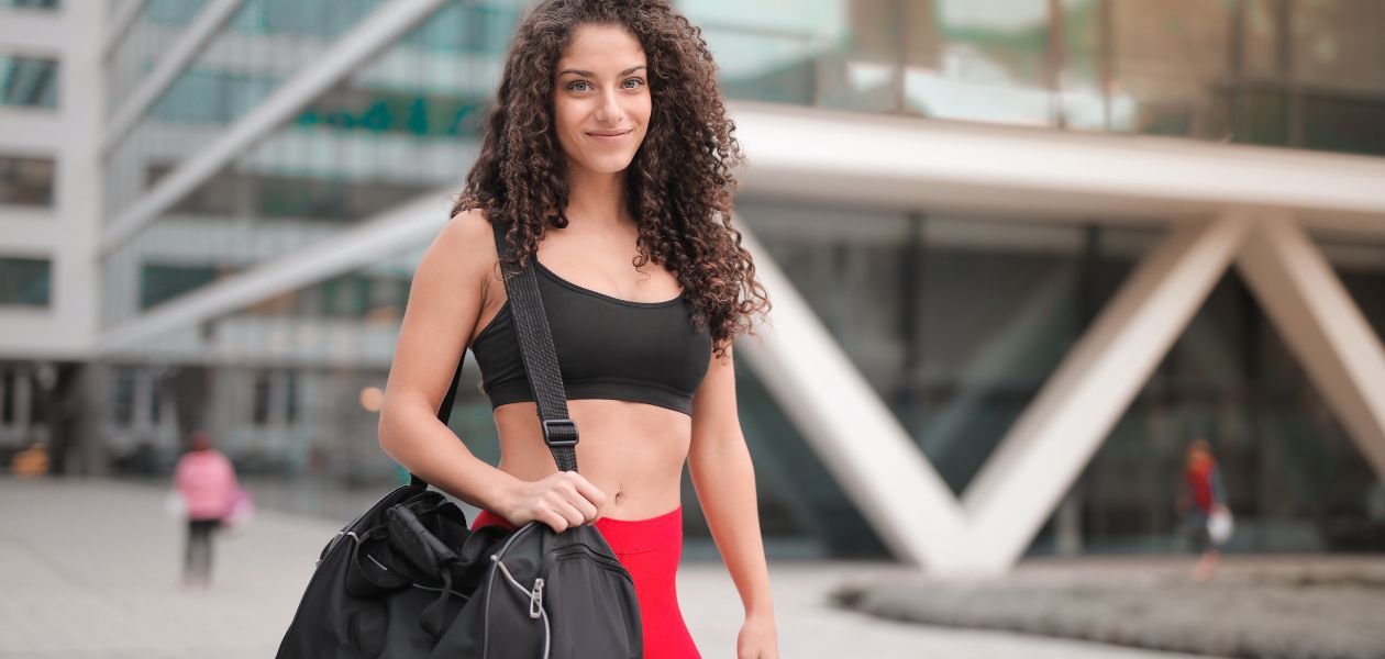 Woman wearing a black sports bra and carrying a bag.