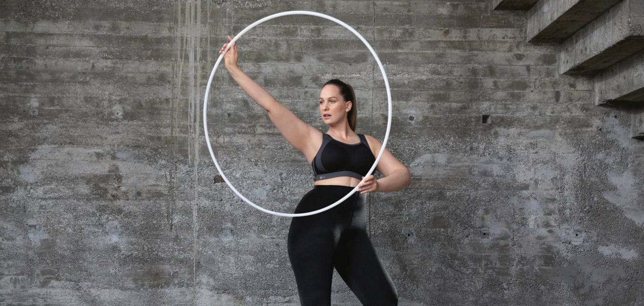 Woman in a sports bra twirling a hola hoop.