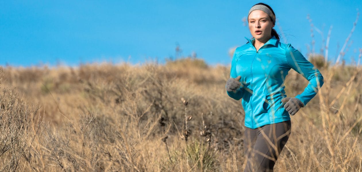 Woman running in the cold in a jacket and gloves.