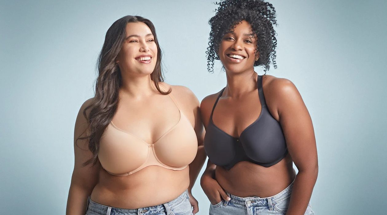 Two women wearing bras and jeans standing together.