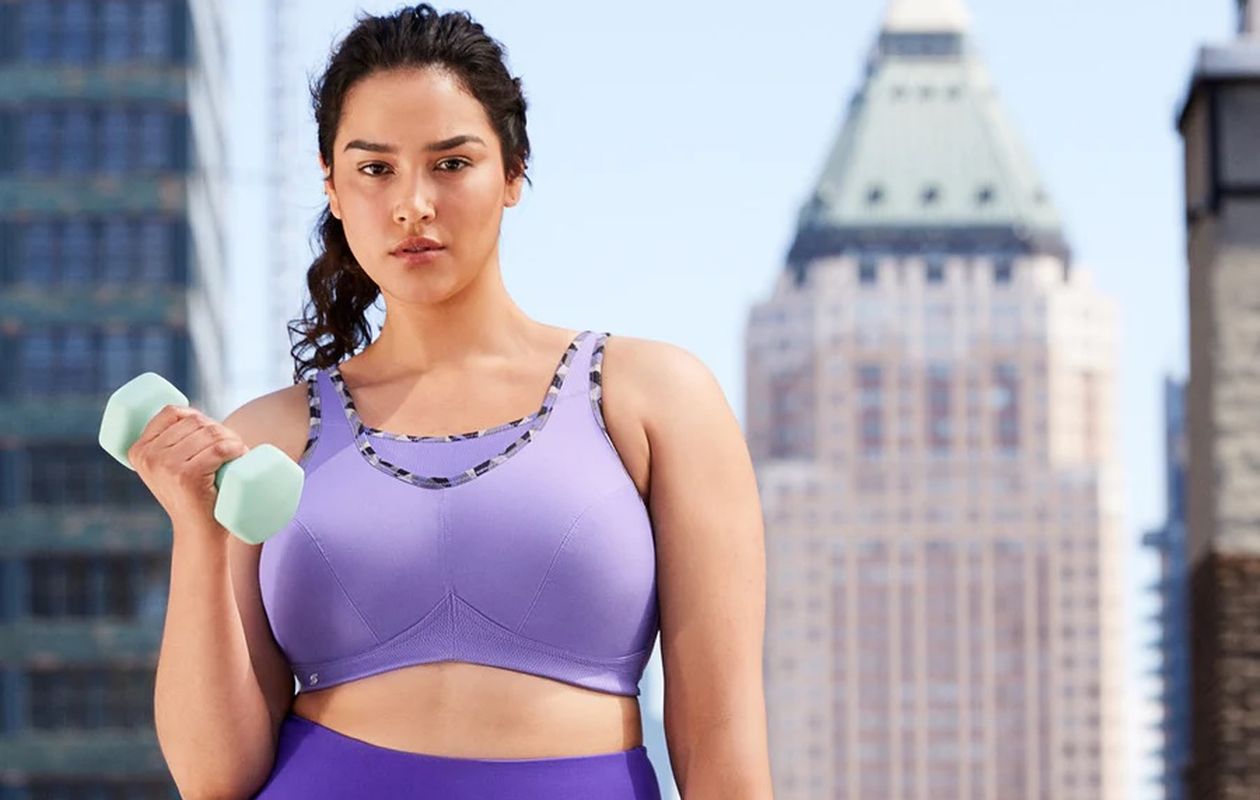 Woman in a Purple sports bra doing weights.
