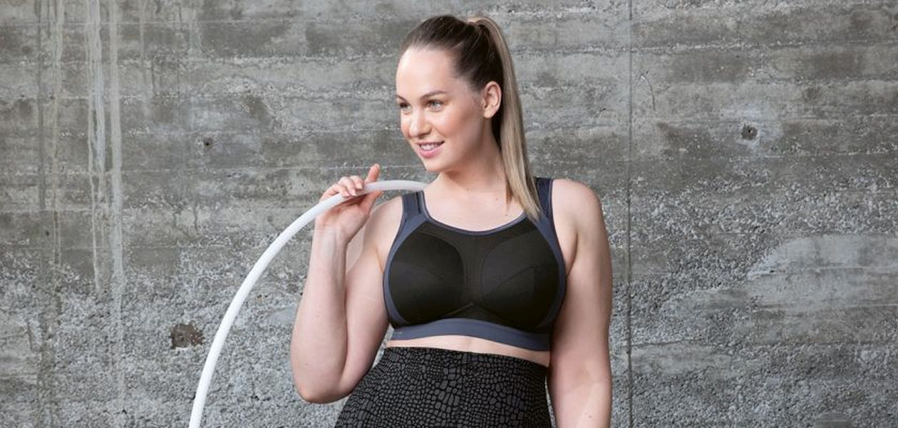 Woman wearing a sports bra holding a hula hoop.