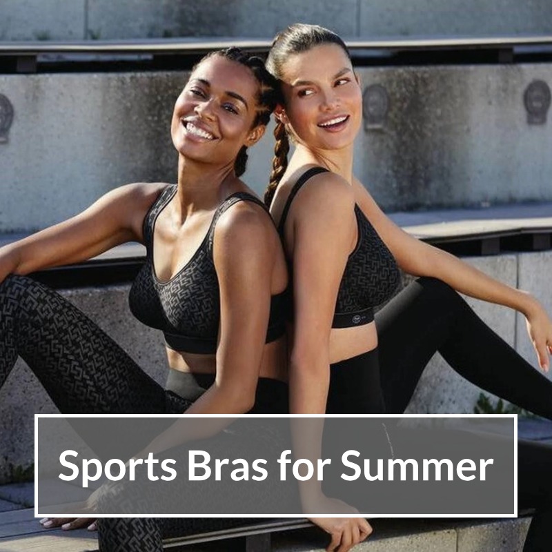 Two women in sports bras sitting back to back.
