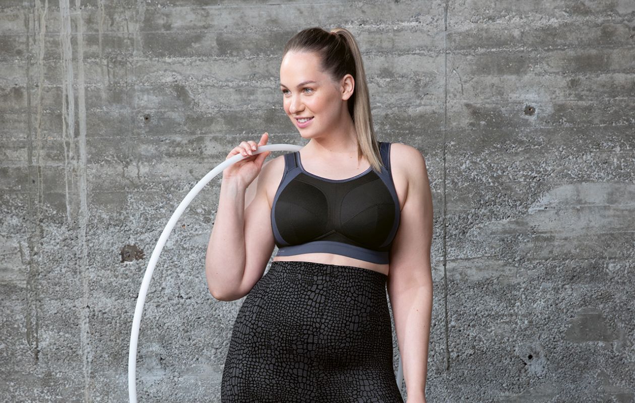 Woman wearing a Black sports bra holding a hula hoop.